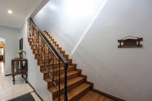 A wooden staircase with a black handrail leading to a landing. - Kota Damansara ICozy Cove Homestay 10 Pax (Petaling Jaya)