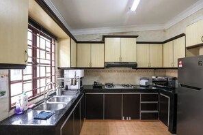 A kitchen with a gas stove, sink, and a refrigerator. - Kota Damansara ICozy Cove Homestay 10 Pax (Petaling Jaya)