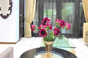A room with a glass coffee table, a vase with flowers, and a mirror on the wall. - Kota Damansara ICozy Cove Homestay 10 Pax (Petaling Jaya)