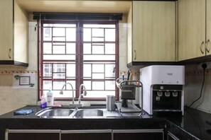 A kitchen with a double sink, a coffee maker, and a water dispenser.