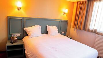 Habitación de hotel con una cama grande, dos lámparas de noche, una mesita de noche y suelo de madera.