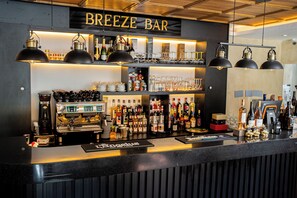 A bar with a black counter, shelves with bottles, glasses, and a coffee machine. - BREEZE HOTEL (Calais)