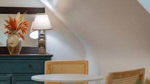 A small, cozy room with a round table and two chairs, a teal cabinet, and a lamp. - *Whole House* | 4-BR Home | 2 Kitchens + Free WiFi (Lynchburg)