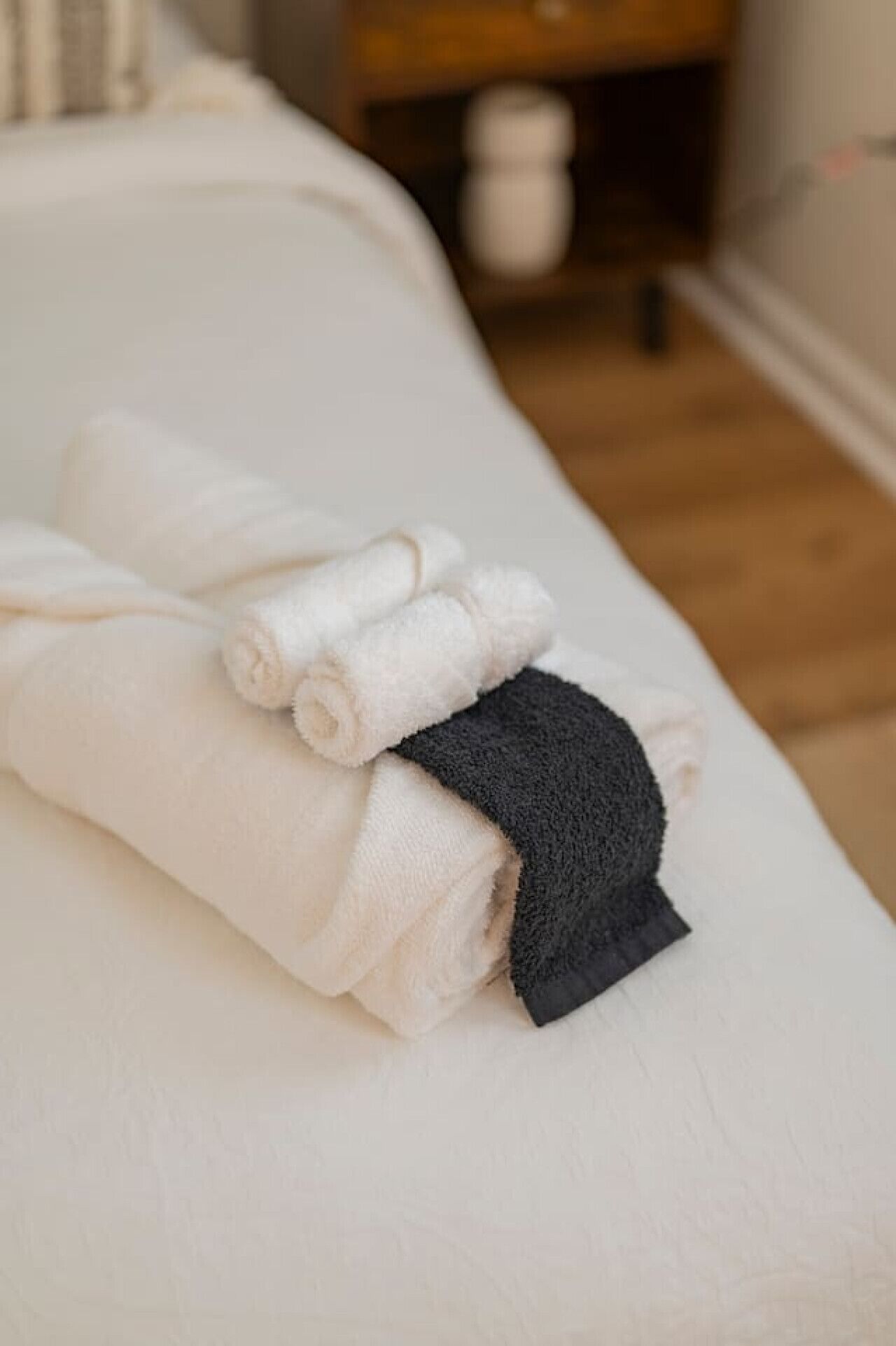 A neatly made bed with white and dark gray towels.
