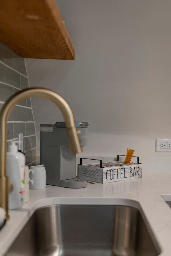 Una cocina con un lavamanos de acero inoxidable, un letrero que dice 'Coffee Bar' y una cafetera.