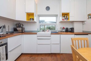 Une cuisine compacte avec des meubles blancs, un four à micro-ondes, une cuisinière et une fenêtre donnant sur un beau paysage.