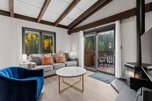 A modern living room with a sofa, blue armchair, and a fireplace. - Top Floor Condo with Scenic Mountain Views! 2 Minute Walk to Nearest Ski Lift (Keystone)