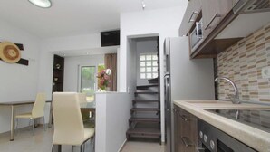 Eine moderne Küche mit Edelstahlgeräten, ein Essbereich mit Tisch und Stühlen sowie eine Treppe, die zu einer weiteren Ebene führt.