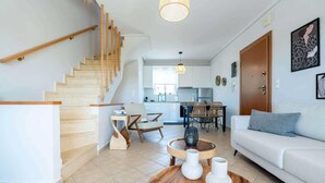 Una sala de estar moderna con una escalera, un comedor y una cocina al fondo.