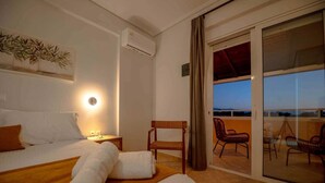 Una habitación de hotel con cama, mesita de noche, silla y balcón con sillas.