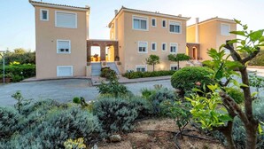 Un edificio residencial de dos plantas con fachada simétrica, múltiples ventanas y una entrada central con escalones.