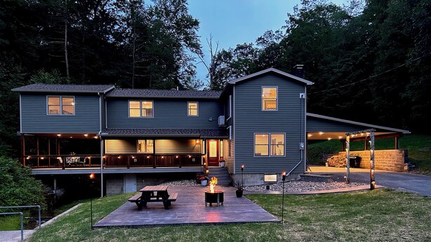 Une maison à deux étages dotée d’un patio couvert, d’un foyer extérieur et d’un espace barbecue.