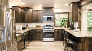 Une cuisine moderne avec des meubles en bois foncé, des appareils électroménagers en acier inoxydable et un plan de travail en granit.