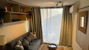 A modern living room with a sofa, a coffee table, and a decorative shelf. - NR APART TOCORNAL (Santiago)