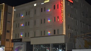 Un hotel con un llamativo letrero que dice 'HOTEL', varias ventanas y un símbolo de corona sobre la entrada.