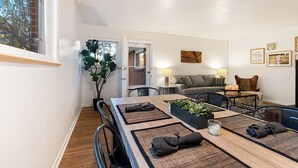 Un espace repas moderne avec une table en bois, des sets de table en fibres tressées et une plante en pot.