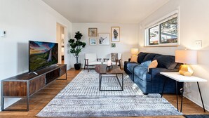 Un salon moderne avec un téléviseur à écran plat, un canapé bleu, une table basse et une plante en pot.