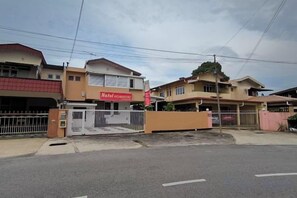 A residential area with a gated entrance, a visible house with a red sign, and a clear sky. - Natol Homestay - London Foochow Road (Kuching)