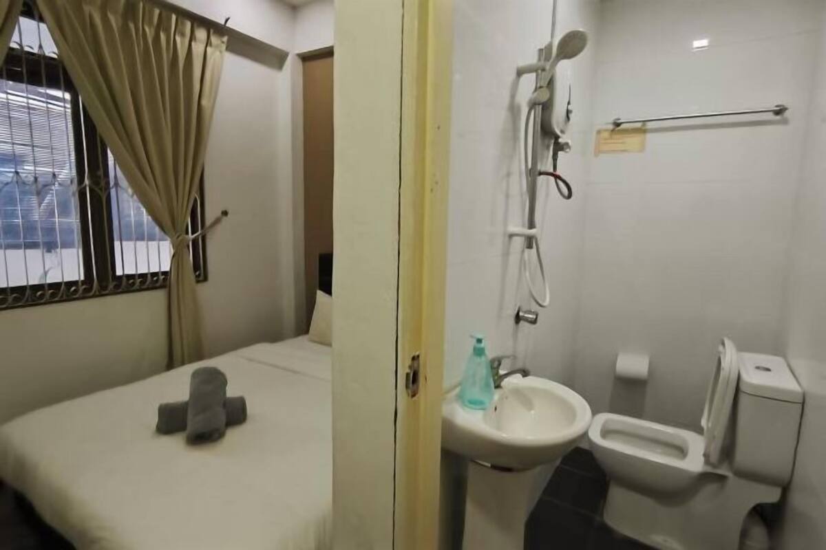 A hotel room with a bed, a bathroom with a sink, toilet, and shower.