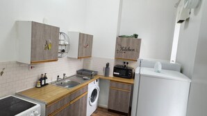 A compact kitchen with a washing machine, a sink, and a small refrigerator.