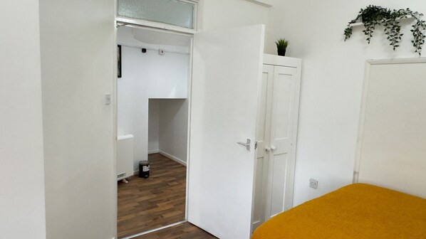 A room with a wooden floor, a white door, and a yellow bed. - Apartment Sleeps 6 With Ensuite (Birmingham)