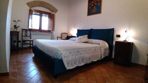 A bedroom with a bed, a chair, a table, a window, and a wall painting. - A few km from Siena Dietro le Mura vacation home in Colle Val d'Elsa (Colle di Val d'Elsa)