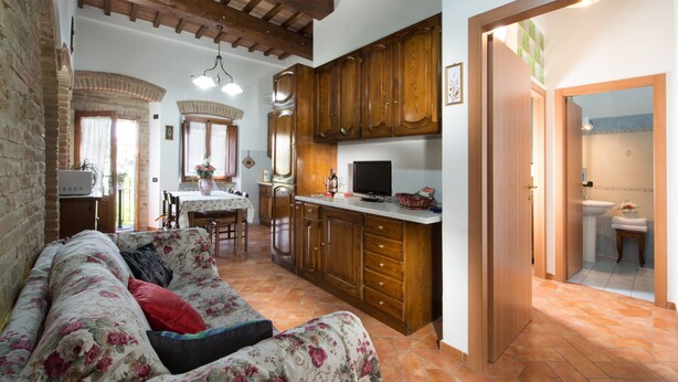 A cozy living room with a floral sofa, wooden cabinets, and a television. - A few km from Siena Dietro le Mura vacation home in Colle Val d'Elsa (Colle di Val d'Elsa)