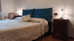 A neatly made bed with a patterned bedspread and pillows, a dark blue headboard, and a bedside table with a lamp. - A few km from Siena Dietro le Mura vacation home in Colle Val d'Elsa (Colle di Val d'Elsa)