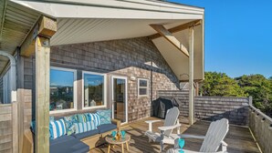 Eine überdachte Terrasse mit Sitzgelegenheit, Grill und Blick auf die Landschaft.