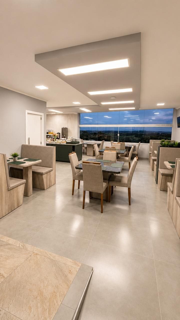 Un comedor moderno con una mesa central rodeada de sillas, una cocina al fondo y vistas de la ciudad a través de amplias ventanas.