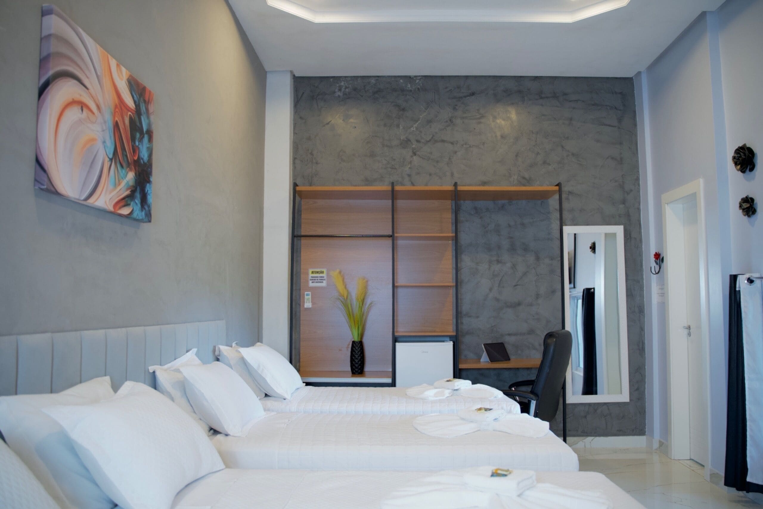 A modern hotel room with a large bed, a desk, and a wardrobe.