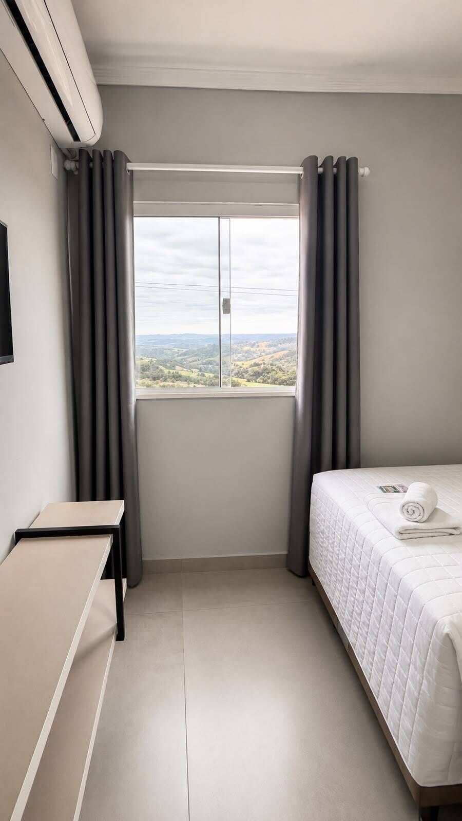 Una habitación de hotel con cama, una mesita y una ventana con cortinas.