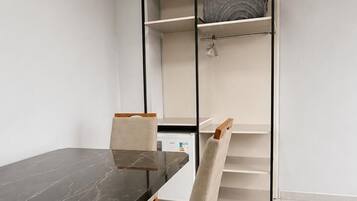 A modern room with a dining table, chairs, a built-in wardrobe, and a white air conditioning unit.