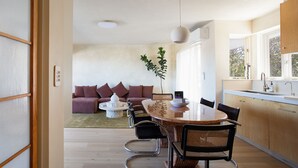 Een moderne keuken met een eethoek, met een ronde tafel, stoelen en een bank met kussens.