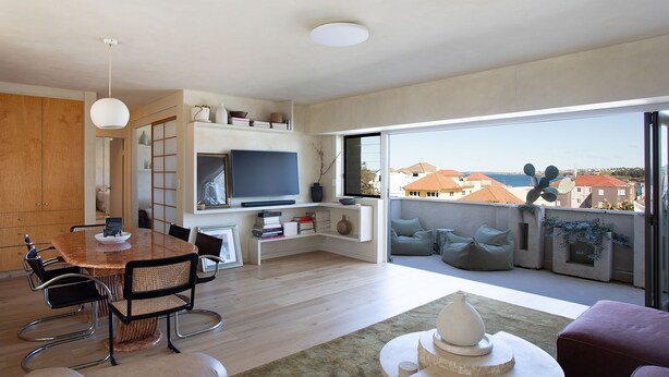 Een moderne woonruimte met een eethoek, een aan de muur bevestigde televisie en een balkon met uitzicht op de stad.