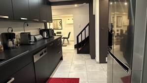 A modern kitchen with dark cabinets, a stainless steel refrigerator, and a red patterned rug.