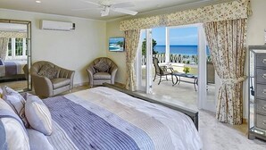 A bedroom with a large bed, two armchairs, a dresser, and a balcony with a view of the sea. - Celebration Villa with Private Pool & Sunset Views (Mount Standfast)