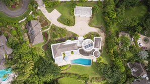 An aerial view of a large, modern house with a swimming pool, surrounded by lush greenery and a well-maintained lawn. - Celebration Villa with Private Pool & Sunset Views (Mount Standfast)