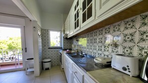 Una cocina con gabinetes blancos, una ventana y salpicadero de azulejos.
