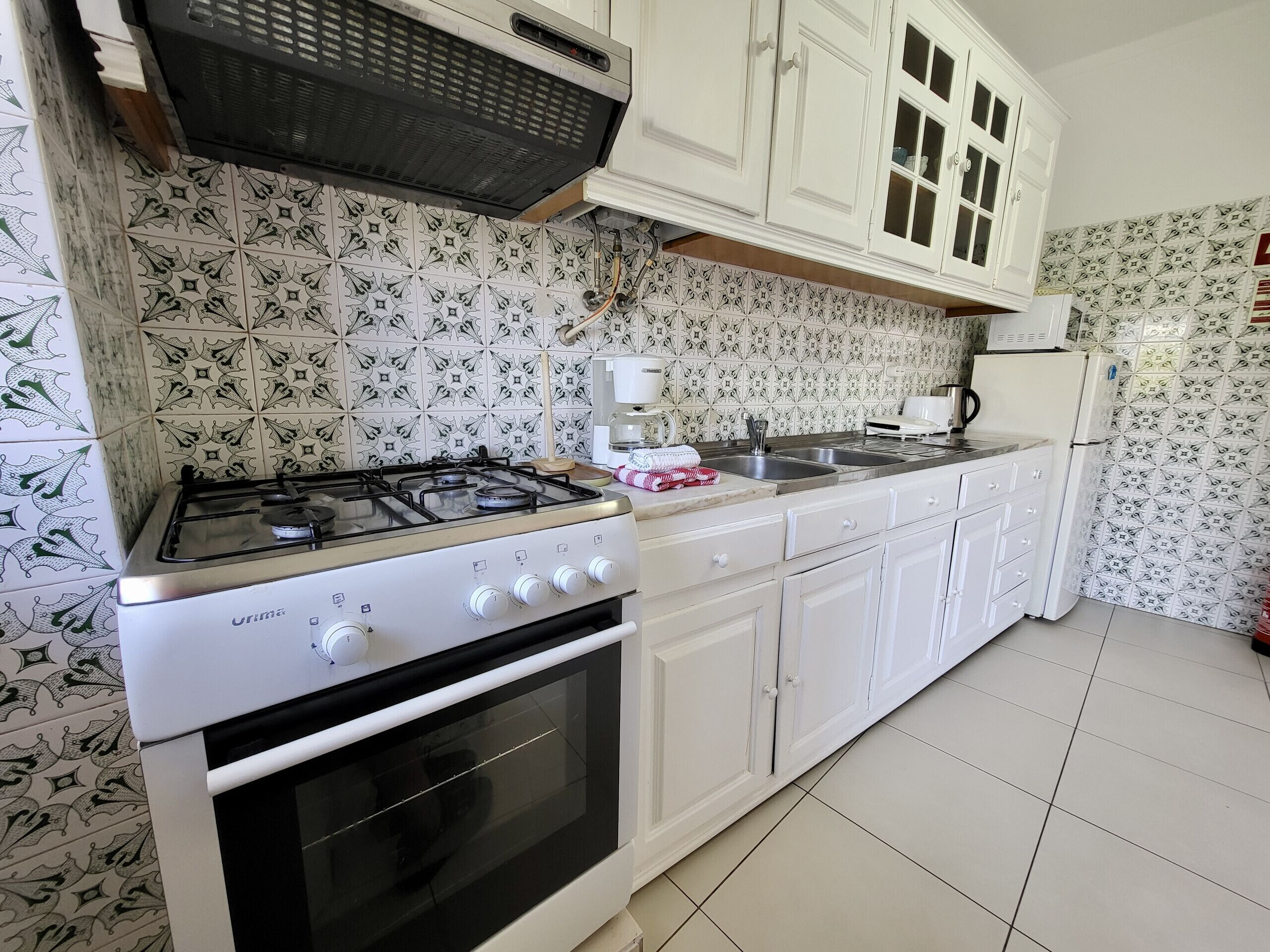 A kitchen with white cabinets, a gas stove, an oven, and a microwave.