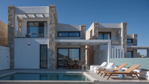 Una casa moderna de dos pisos con piscina, mobiliario exterior y detalles de piedra.