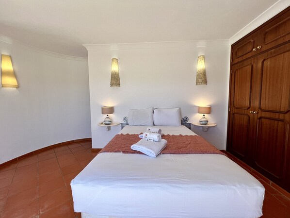 A hotel room with a large bed, two bedside lamps, a wooden wardrobe, and a wall-mounted towel rack. - Alvor Traditional Villa by Homing (Portimão)