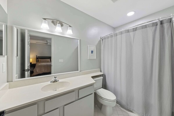 A bathroom with a white sink, a toilet, and a shower curtain.