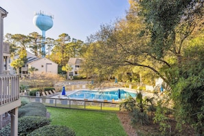 A swimming pool surrounded by a fence, with a view of residential buildings and a water tower in the background.