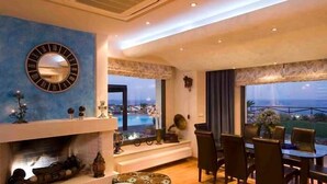 Ein modernes Wohnzimmer mit Kamin, Essbereich und großen Fenstern mit Blick ins Freie.