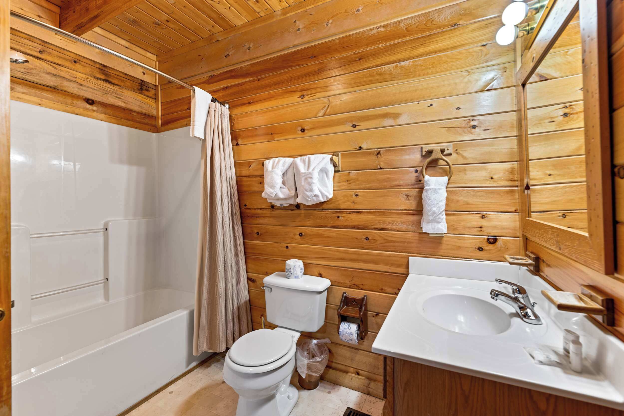 Un baño con paneles de madera, una bañera, un inodoro y un lavamanos.