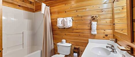 Un baño con paneles de madera, una bañera, un inodoro y un lavamanos.
