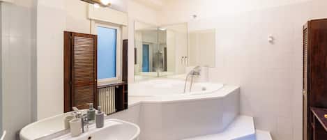 A modern bathroom with a large mirror, a bathtub, and a sink.
