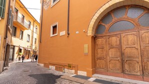 A cobblestone street with a large wooden door and a window with a decorative arch. - Residenza Serego - affaccio scavi Romani (Verona)
