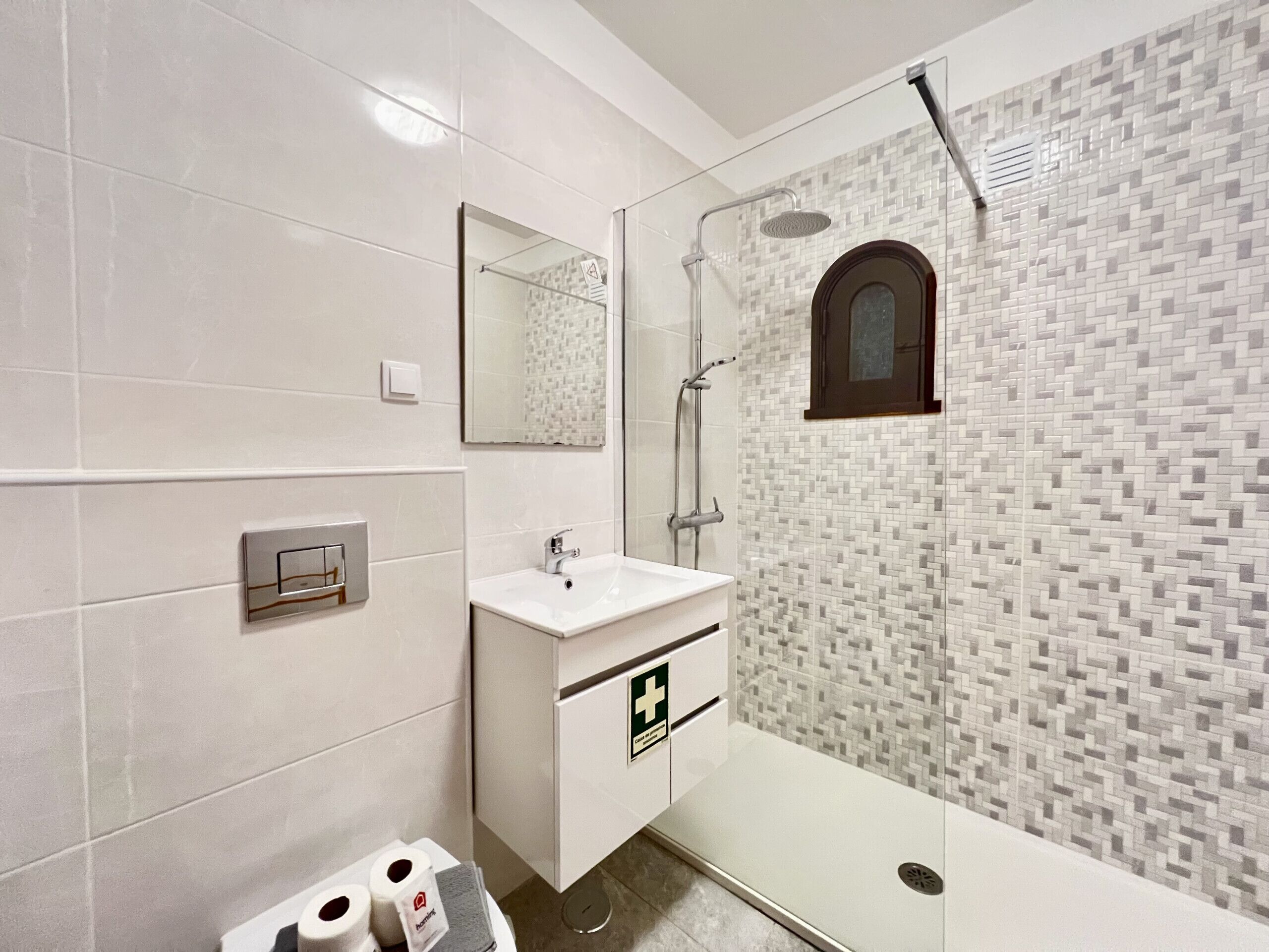 A modern bathroom with a glass-enclosed shower, a white vanity with a mirror, and a tiled backsplash.